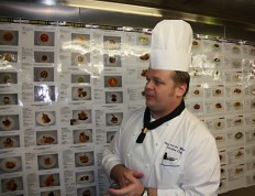 Executiv Chef Steve van der Merwe vor Fotos aller auf der Celebrity Eclipse servierten Gerichte