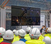 Gäste und Werftarbeiter beobachten das Anschweißen der Glücksmünzen